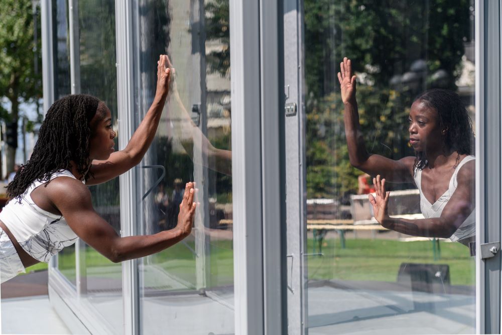 two dancers performing 'bonded' inside perspex glass box