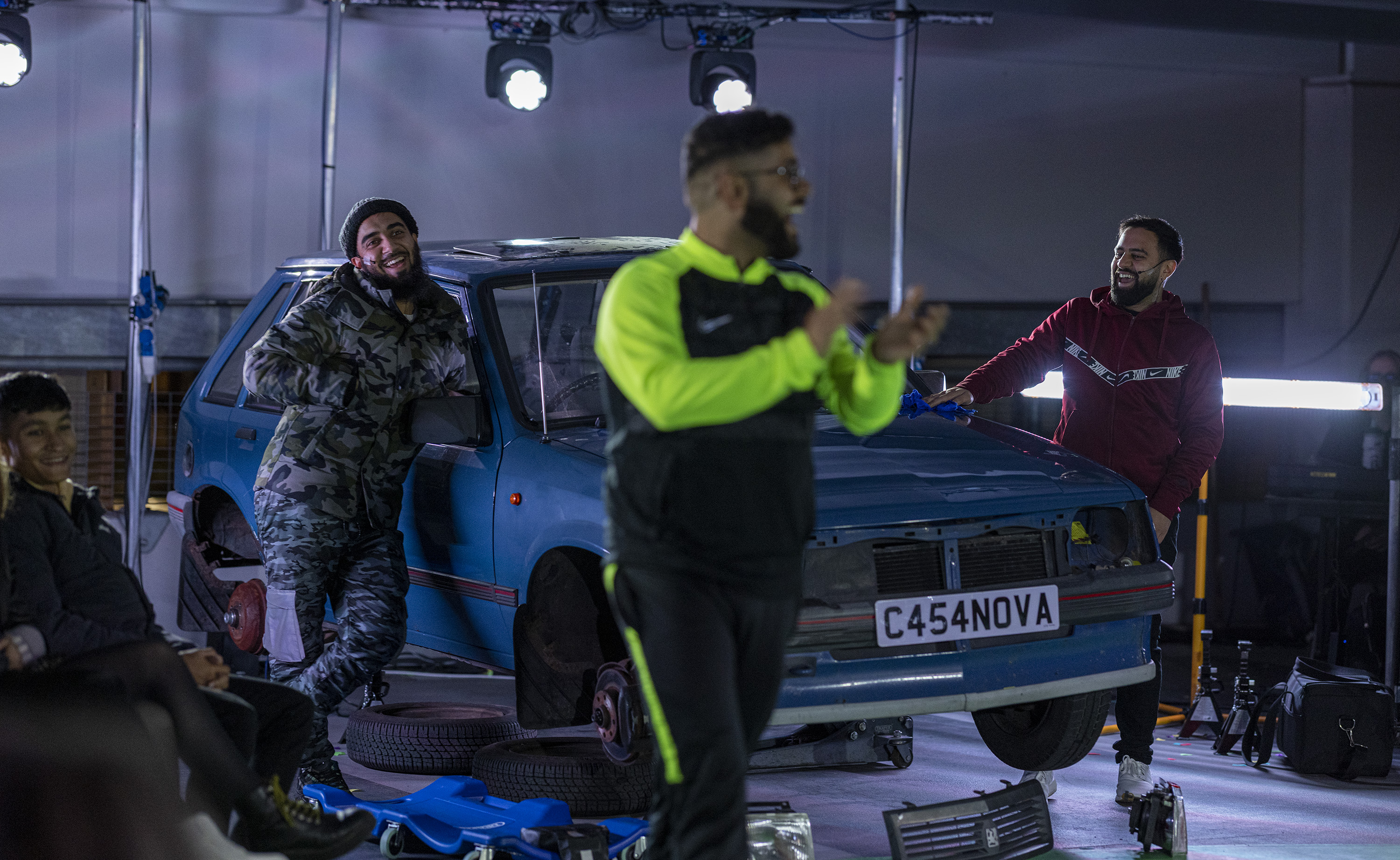 the performers of Peaceophobia smile and applaud in front of their modified Vauxhall Nova